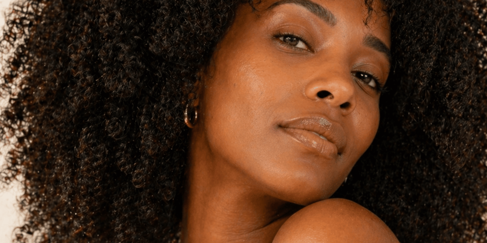 Woman with voluminous naturally curly hair styled and defined. warm studio lighting.