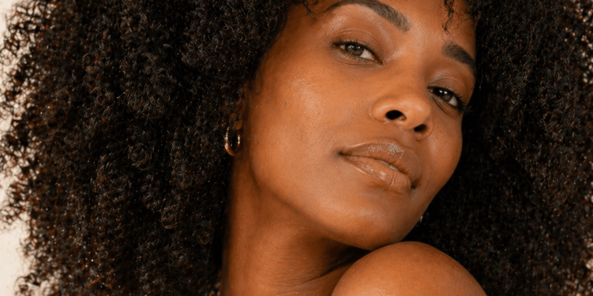 Woman with voluminous naturally curly hair styled and defined. warm studio lighting.